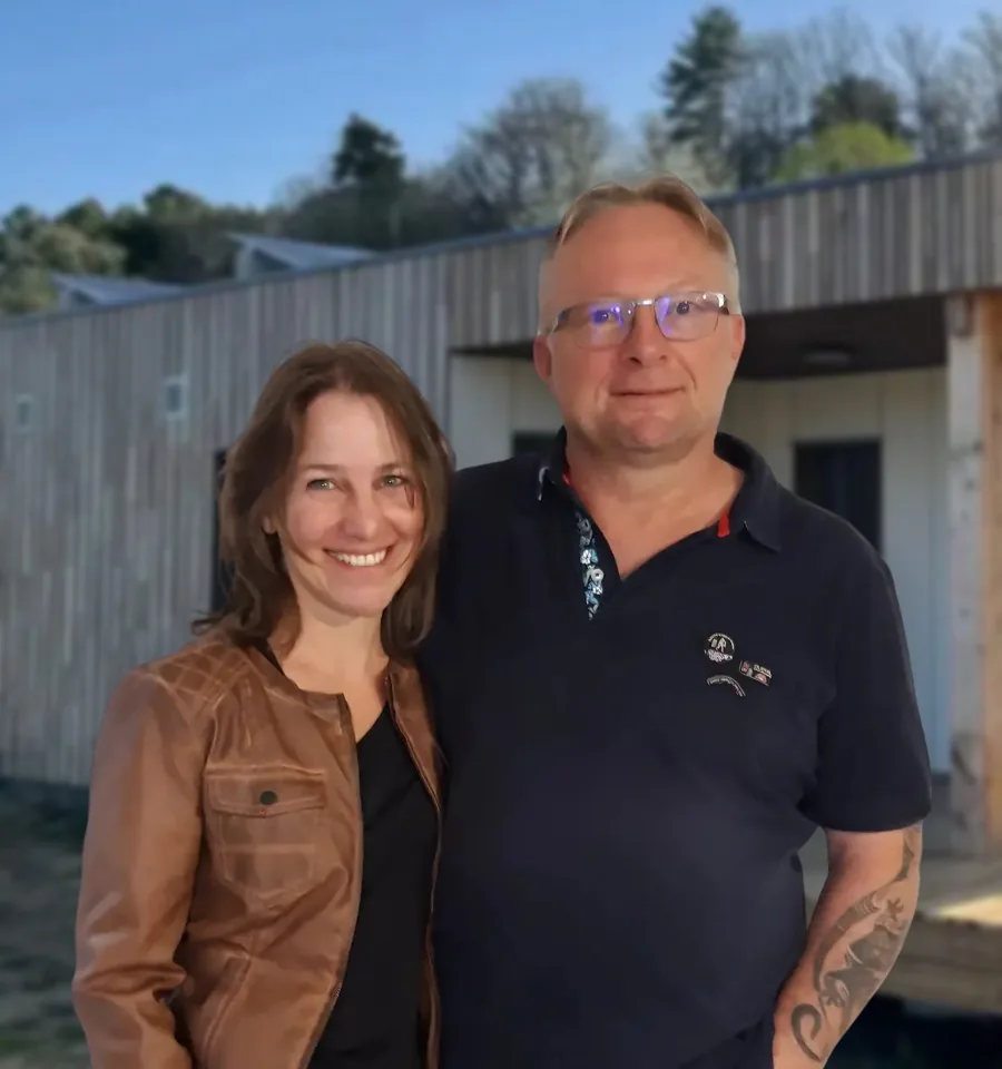 Denis et Sylvie Rogey, fondateurs d'ACMT (photomontage devant une maison passive en ossature bois réalisée par ACMT)