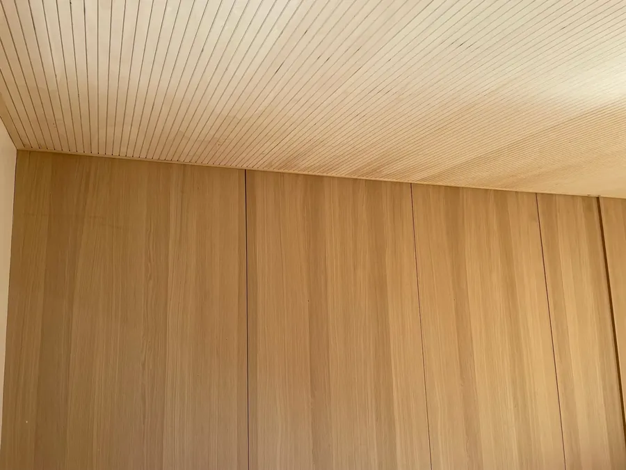 Habillage mural et plafond en lames de bois clair dans une pièce terminée