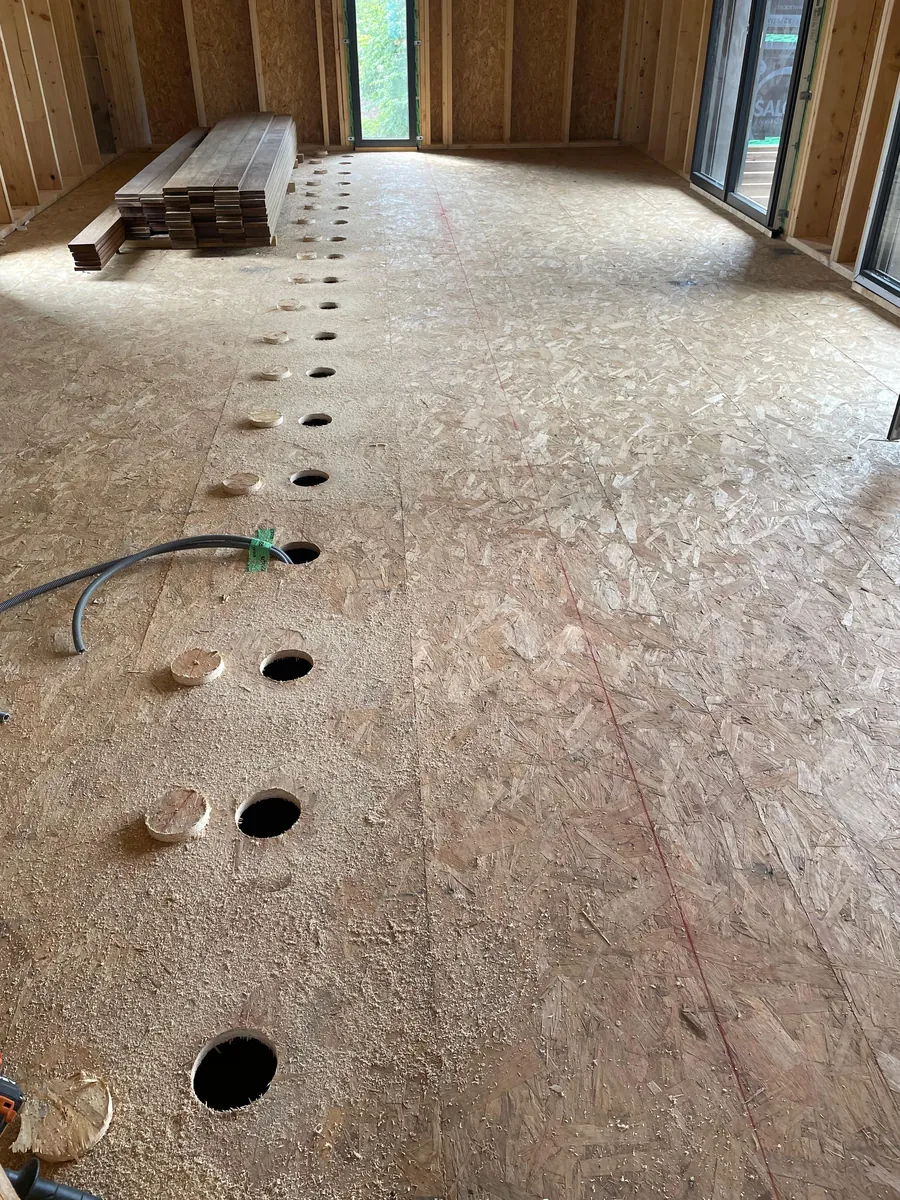 Plancher en OSB percé de trous d'insufflation, alignés le long de la paroi