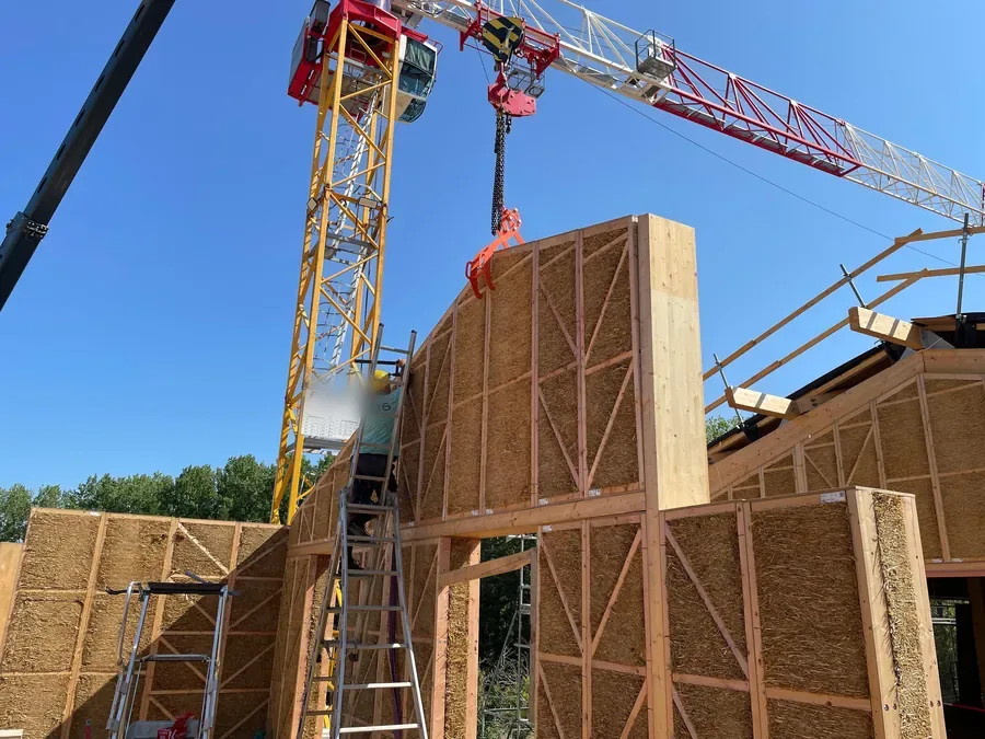 Levage d'un mur bois-paille à la grue, chantier du Village des Pruniers