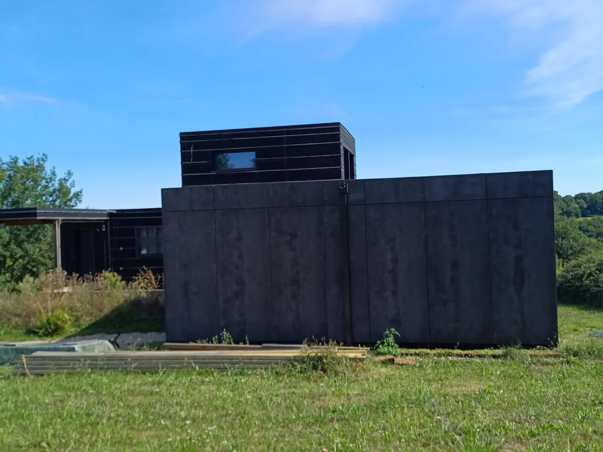 Maison passive en ossature bois avec bardage foncé et volume en surélévation, en Dordogne