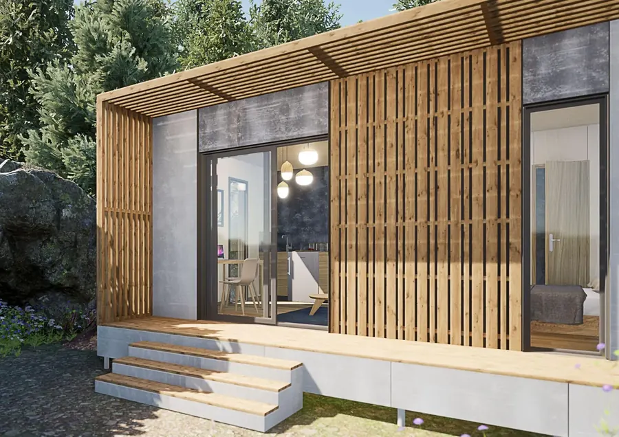 Terrasse bois abritée par une pergola à lames devant la baie vitrée d'un studio ACMT