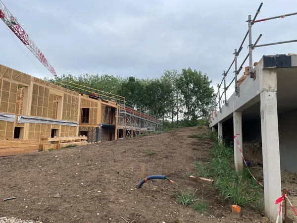 Vue du chantier : bâtiment bois-paille et bâtiment béton voisin