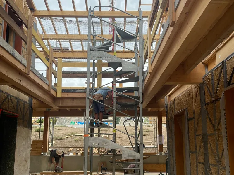 Cour intérieure entre deux bâtiments bois-paille, escalier de chantier et planchers bois