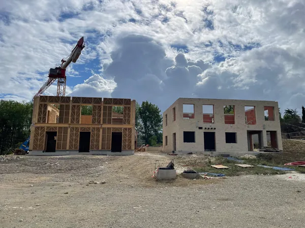 Ossature bois remplie de paille à côté d'un autre bâtiment du chantier