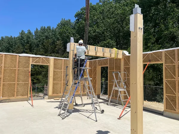 Pose d'une poutre sur un poteau bois, chantier bois-paille