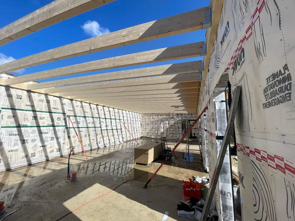 Intérieur de la salle de yoga en chantier, solives de toiture et murs habillés du frein-vapeur