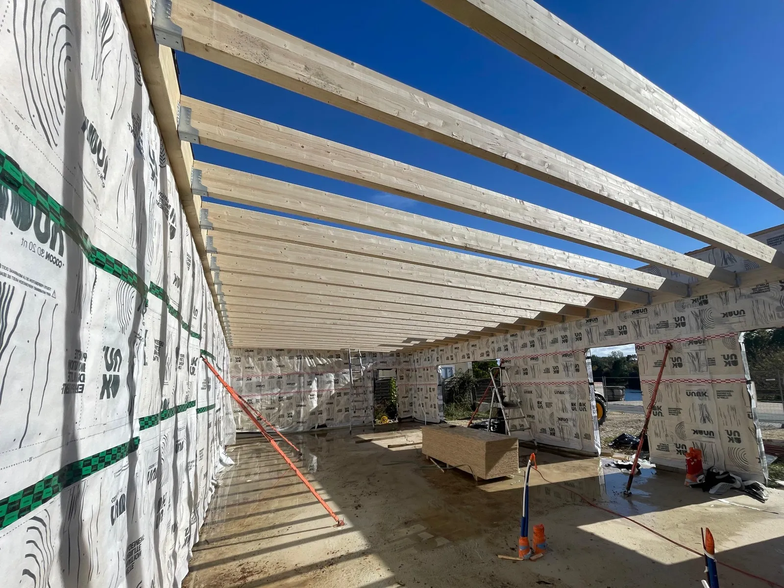 Solives de toiture en bois posées sur les murs à ossature d'une salle de yoga en chantier, ciel bleu